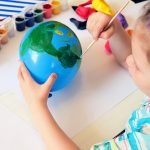 Child making planet for earth day from balloon. drawing blue ball with green continents. Protection of environment, Save our planet. Ecology concept. art learning and education love earth save world